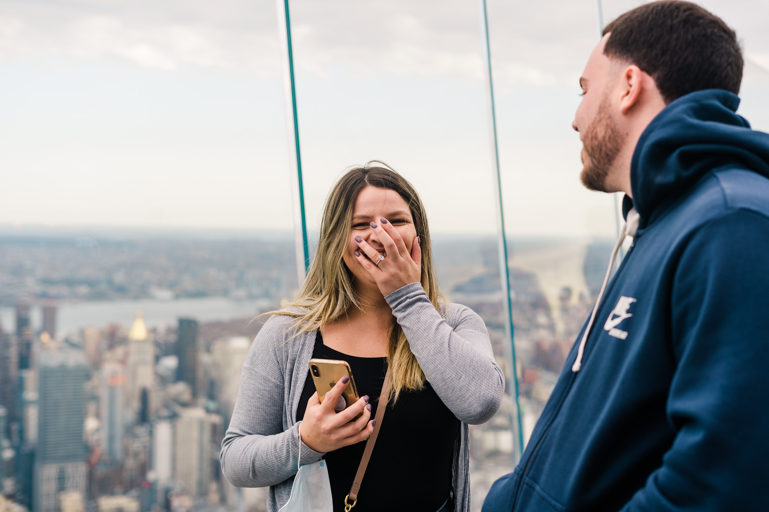 surprised woman with hand over face with a ring on it.