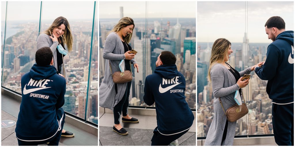 a couple getting engaged at The Edge in Hudson Yards. A woman is in shock as her partner is down on one knee proposing.