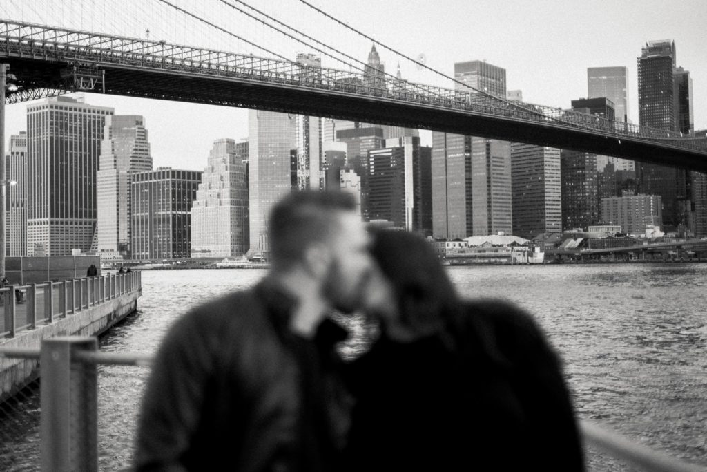 the new york city skyline in focus while a couple is kissing and out of focus