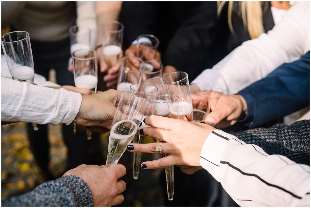 a group of people holding champagne flutes together in a cirlce