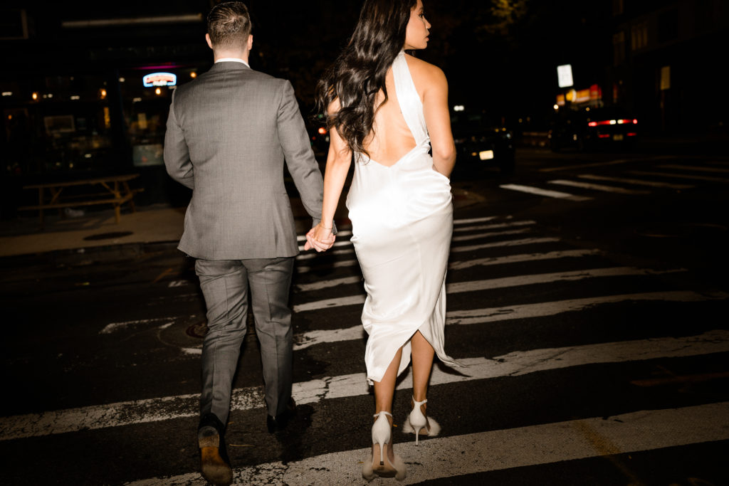 man and woman holding hands while walking through a crosswalk