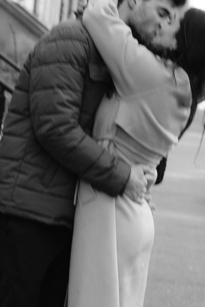 a black and white image of a couple kissing in motion