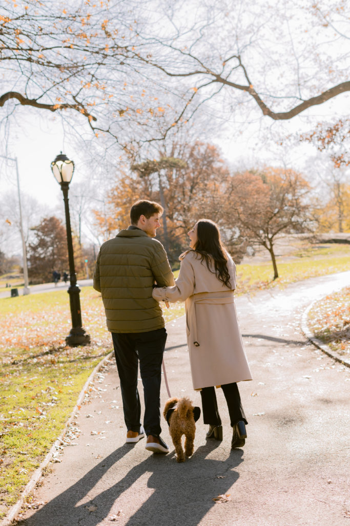 a couple and their dog walking down a path in a park