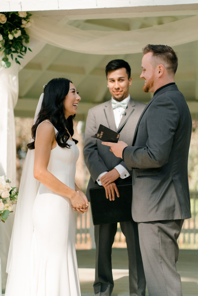 a bride and groom facing each other while they smile and laugh