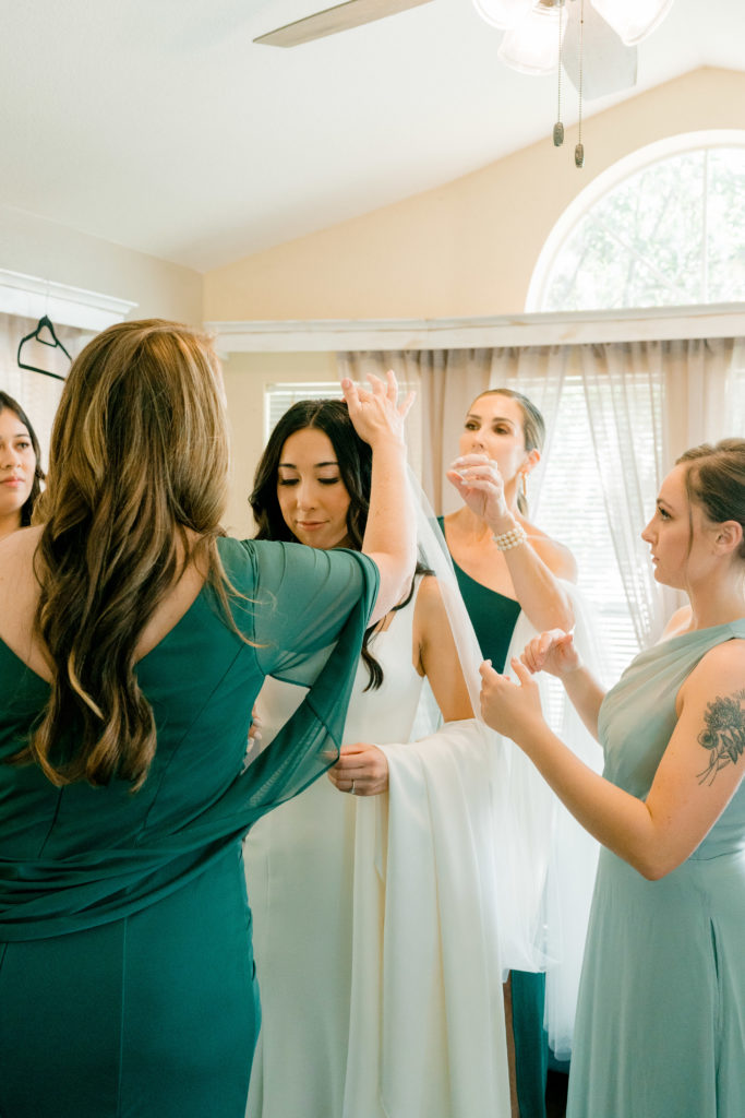 women circled around a bride putting on her veil