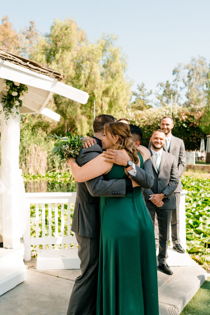 two people hugging a groom with their arms wrapped around each other