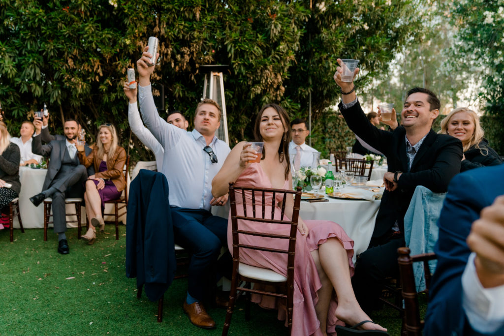 a small crowd of people holding up their glasses and smiling while they toast to each other
