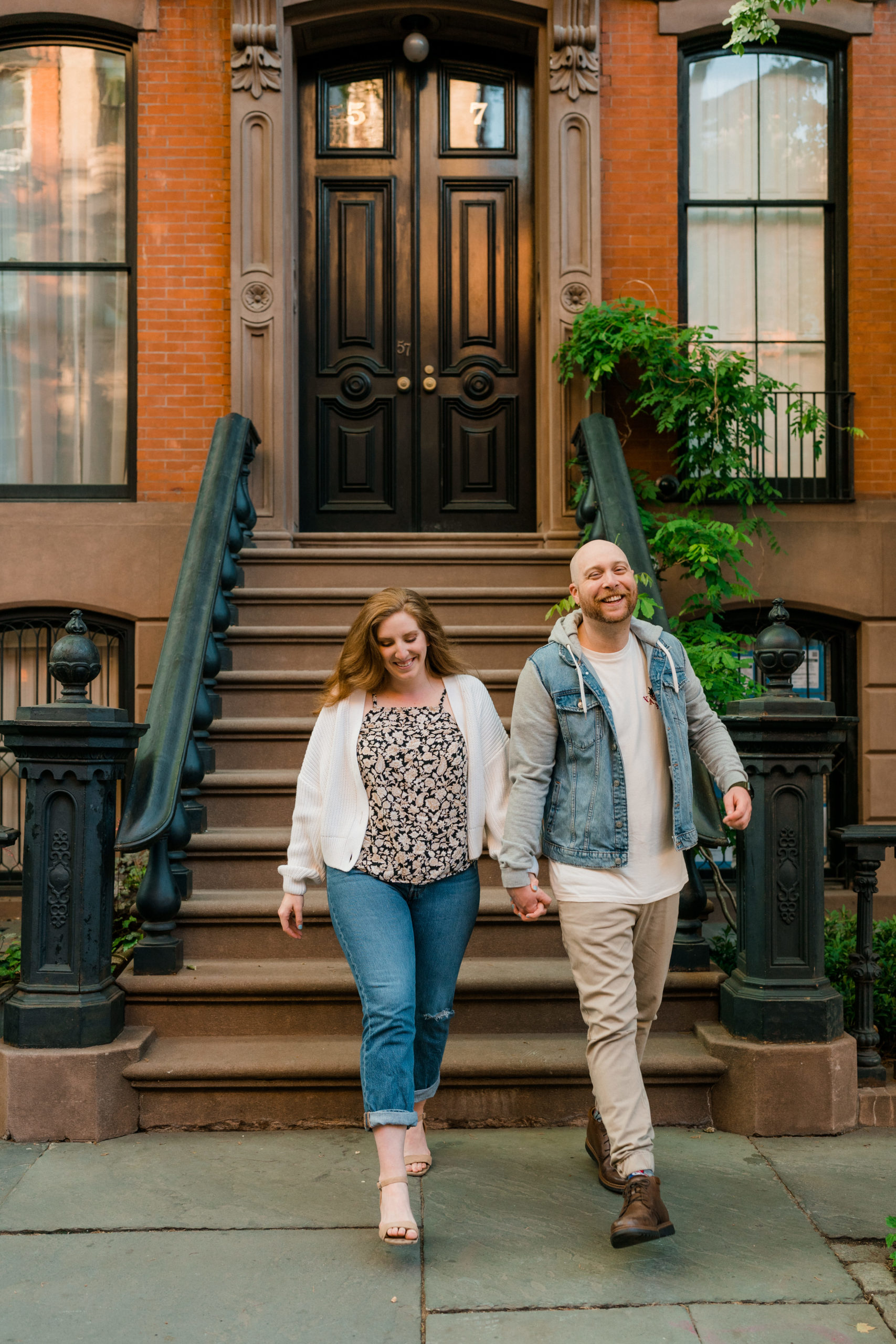 woman and man holding hands while walking down a nyc brownstone stoop