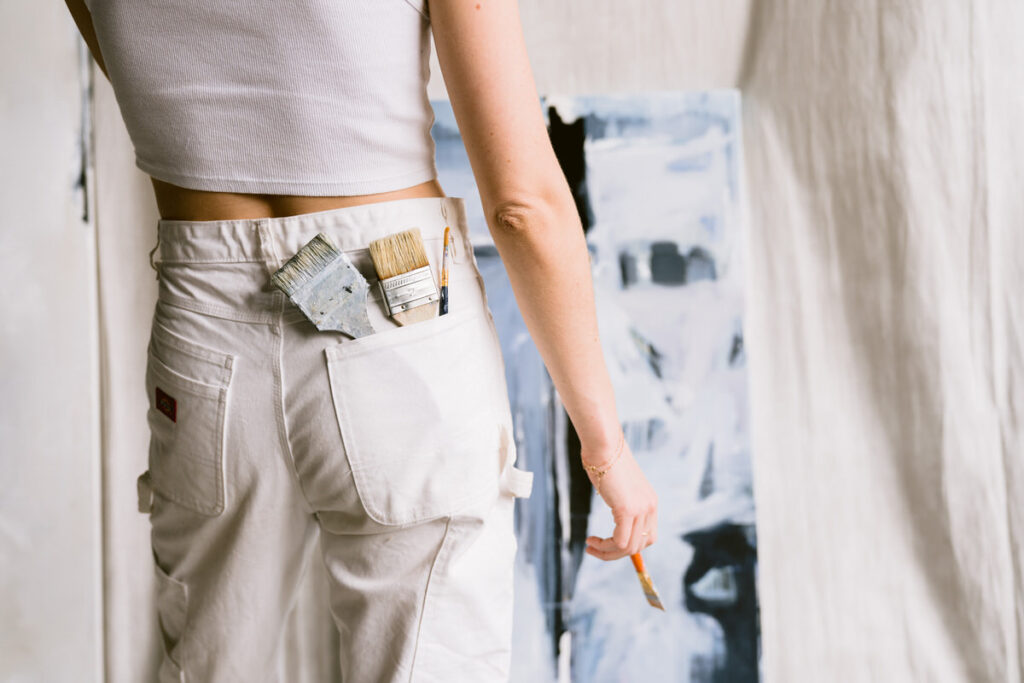 Paintbrushes in the back pocket of an artists jeans.