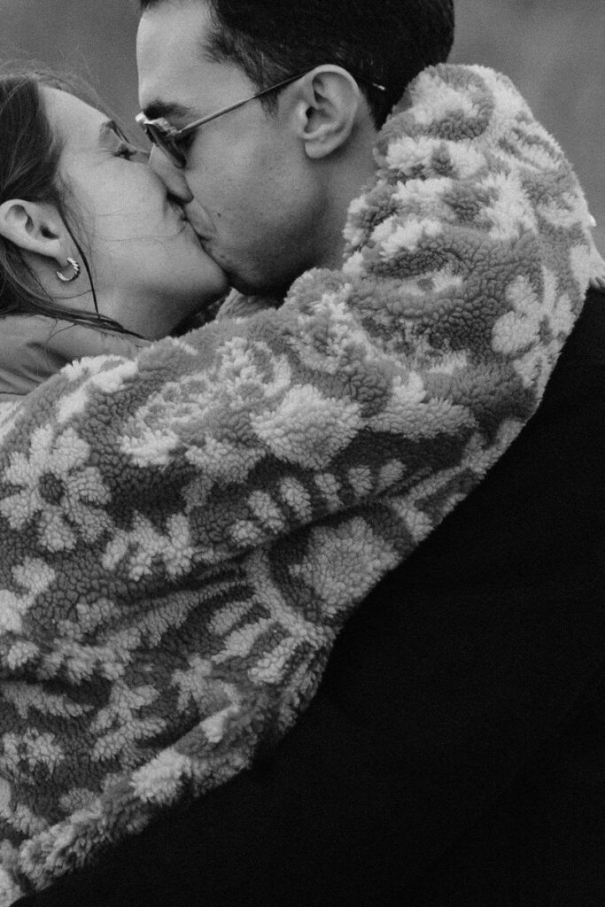 A black and white photo of a couple kissing. 