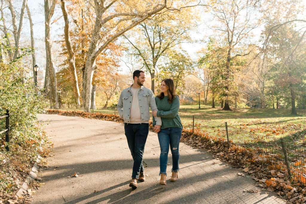 A couple holding hands and walking along a path in a park. 