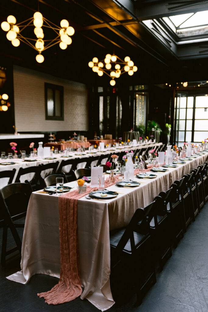Long rectangular wedding reception tables decorated with small flowers. 
