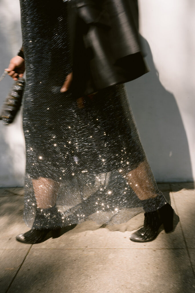 Close-up of a sparkling skirt and black boots with sun reflections, highlighting movement and texture.