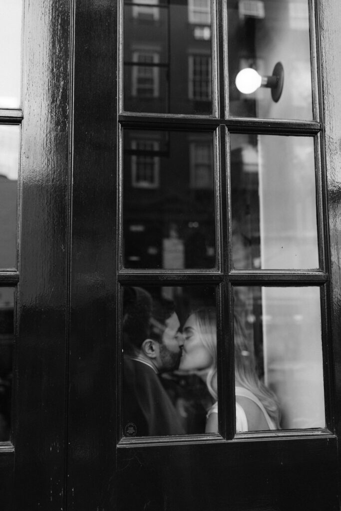 A couple kisses through a window.