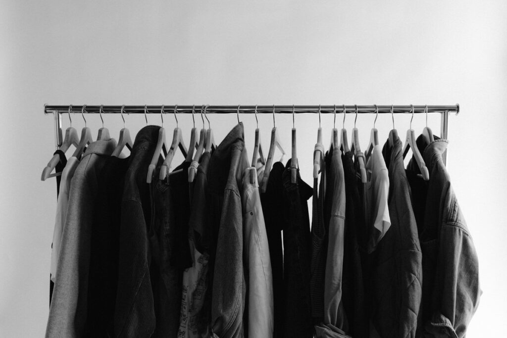 Black and white photo of clothes on a small rack 
