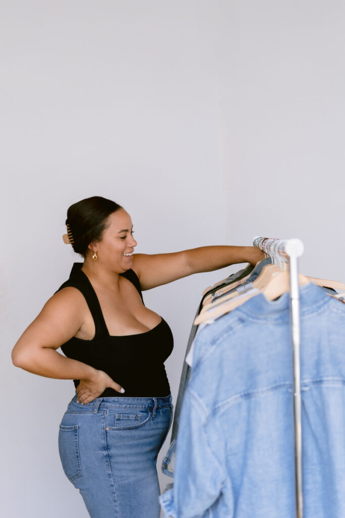 A person with one hand on their hip looking through a rack of clothing 
