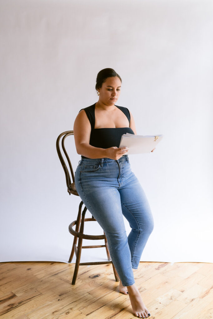 A person sitting on a wooden chair looking at papers 
