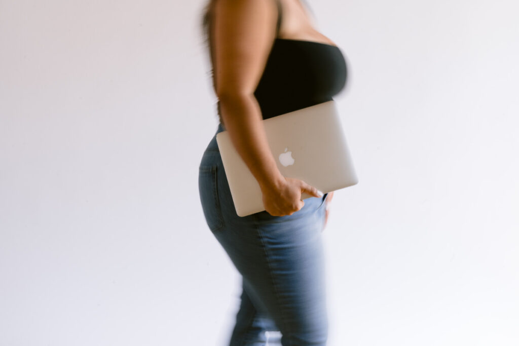 A person walking while holding a laptop with one hand 
