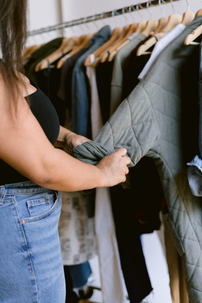 A person rolling up the sleeve on a jacket on a rack 
