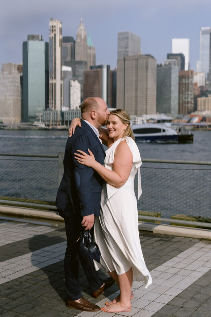 A person kissing their partner's head while holding their shoes 
