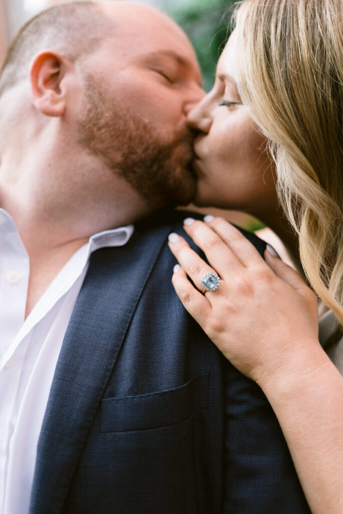 A couple kissing highlighting an engagement ring on one of their fingers