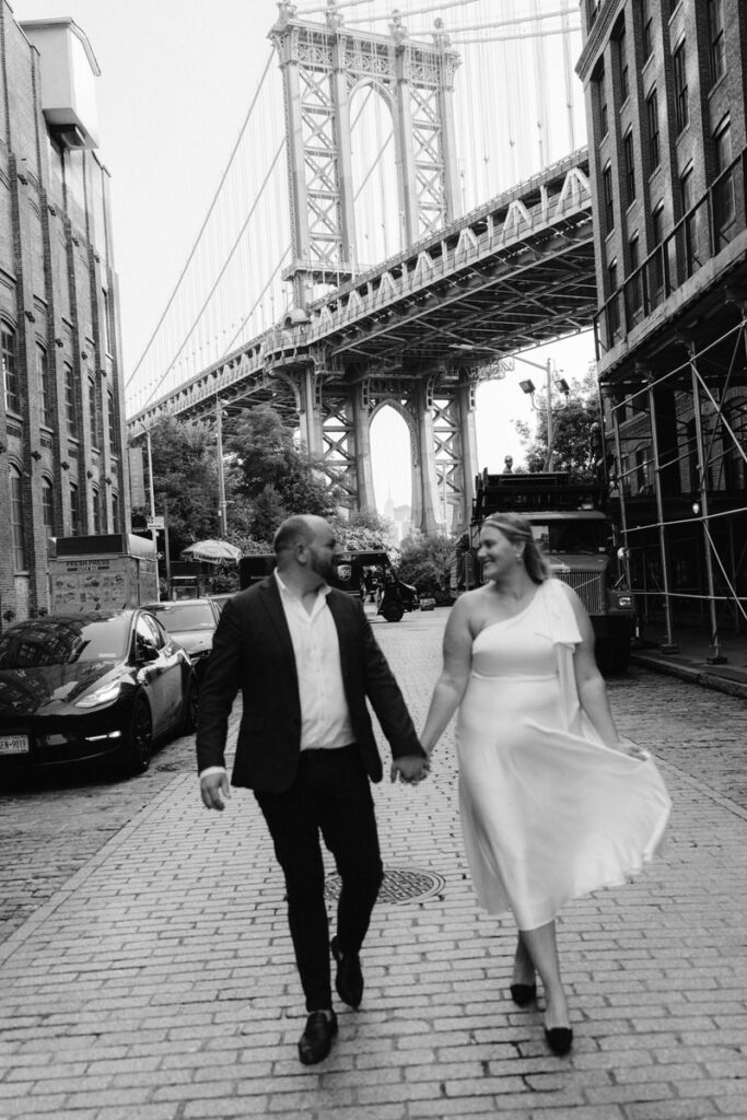 A couple holding hands and walking down a small brick street 