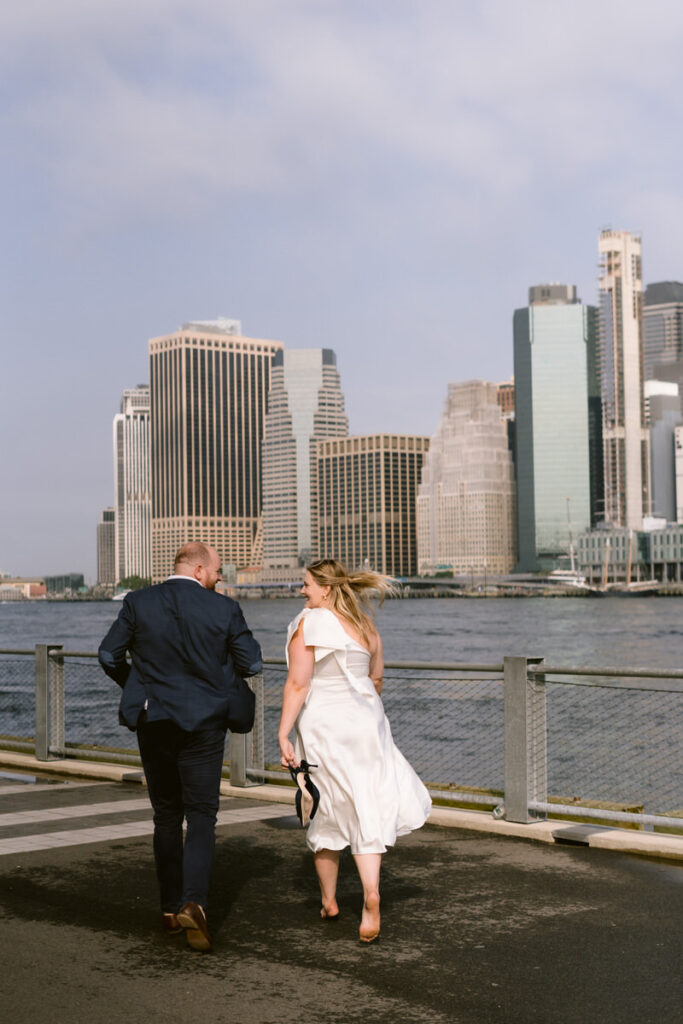 A couple running and smiling together next a rive in NYC