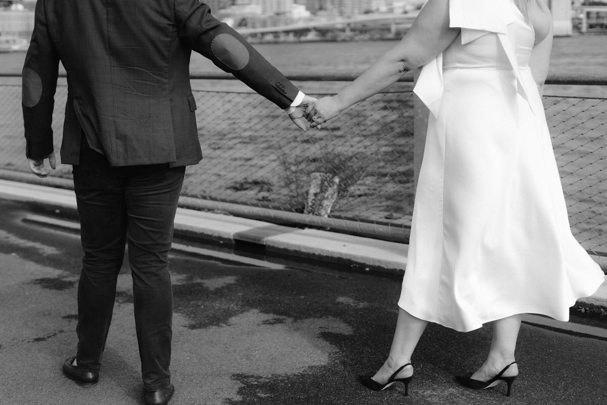 A couple holding hands and walking along a river showing how to prepare for engagement photos