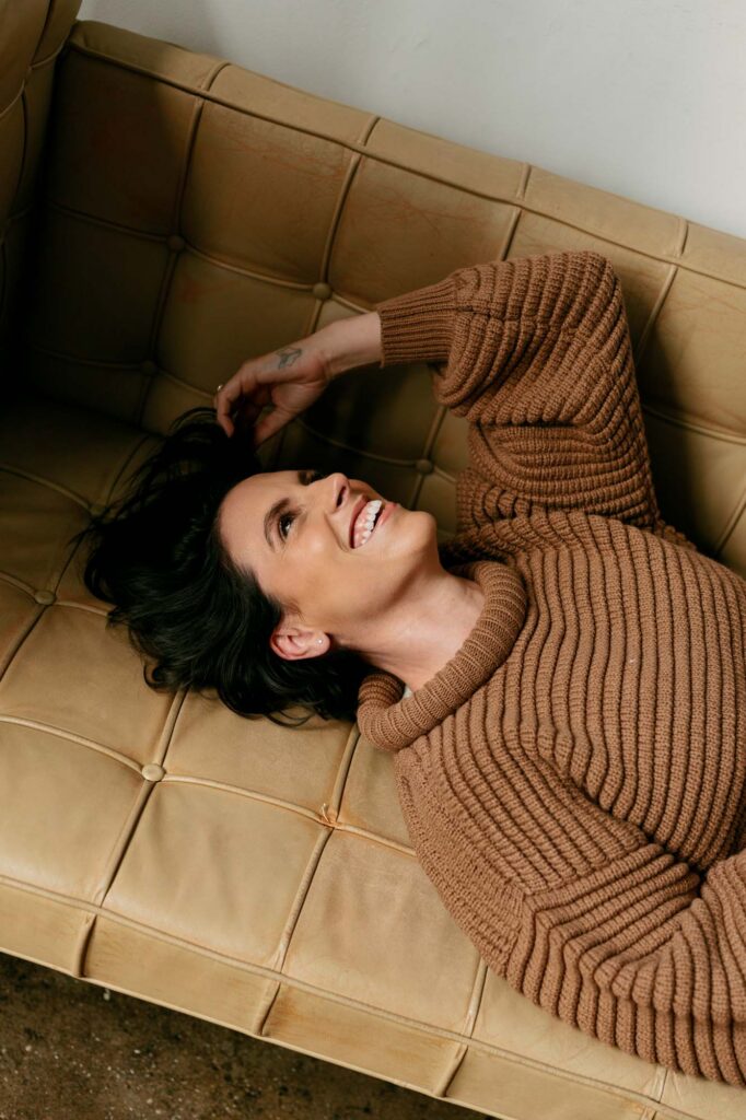 Candid moment of Zay laughing while lying on a leather sofa during her Brooklyn branding session